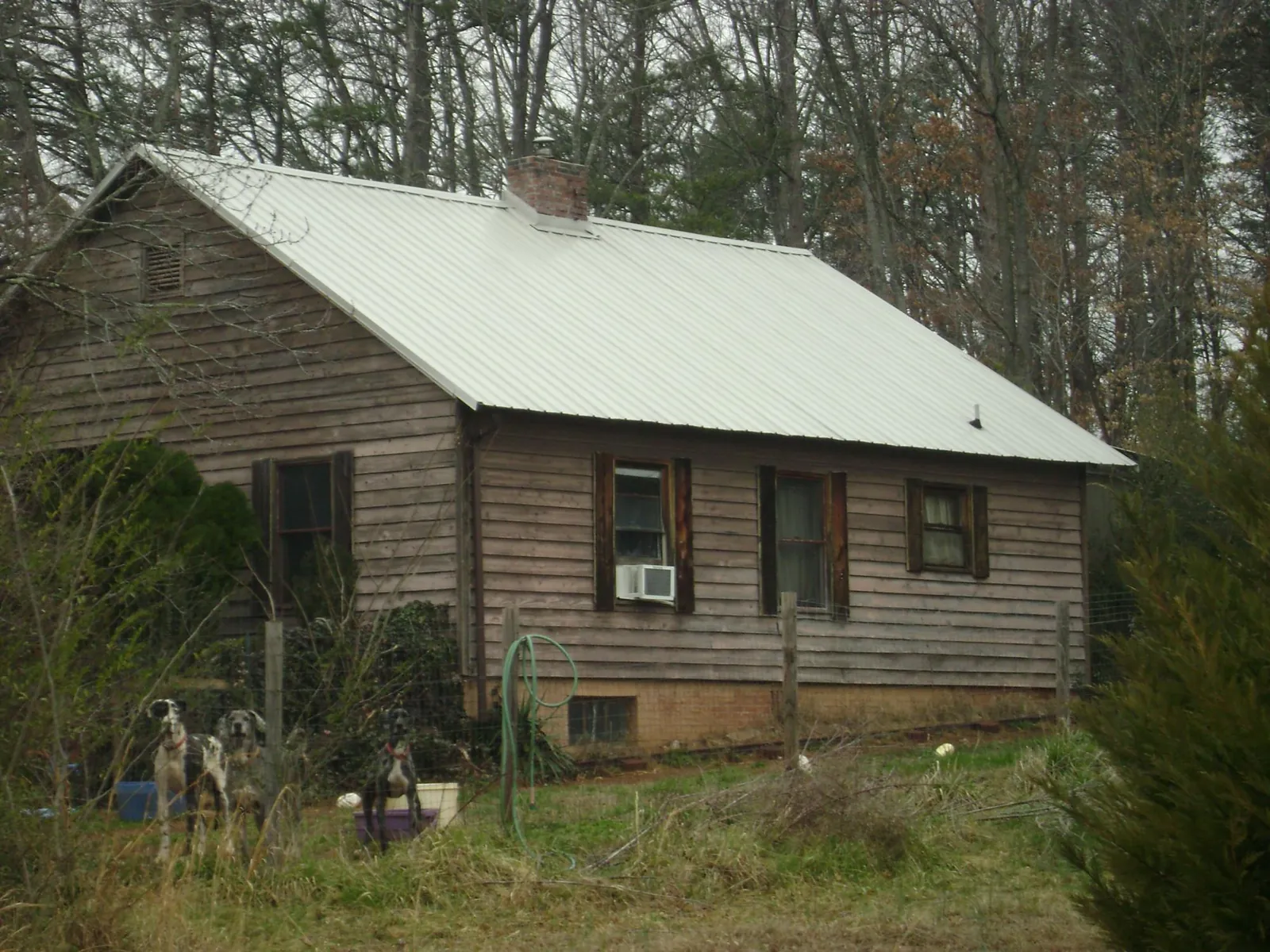 White metal roof on an old wood sided farmhouse, from a Metal Roof Installation job in Matthews