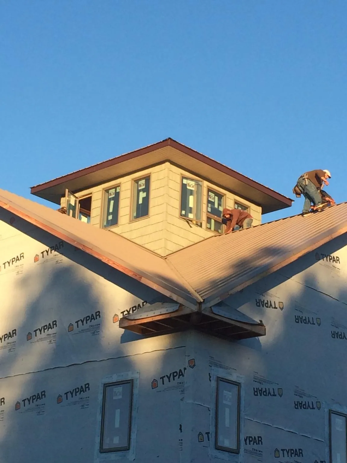 Roofers working around a rooftop cupola on a new metal roof at sunset — Roof Waterproofing in Matthews by Roofing Brothers